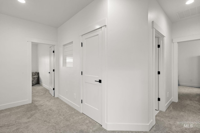 hallway featuring light colored carpet