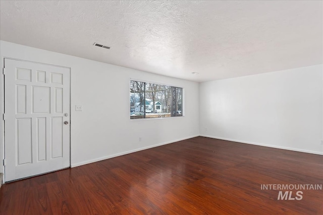 empty room featuring dark hardwood / wood-style floors and a textured ceiling