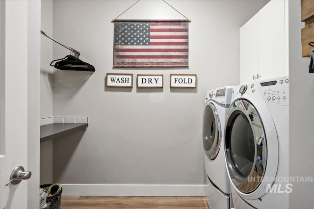 laundry room featuring light wood-type flooring, washing machine and dryer, cabinet space, and baseboards