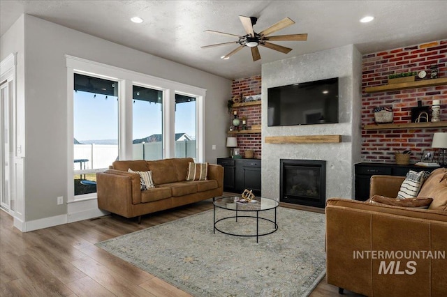 living room featuring recessed lighting, a large fireplace, wood finished floors, a ceiling fan, and baseboards