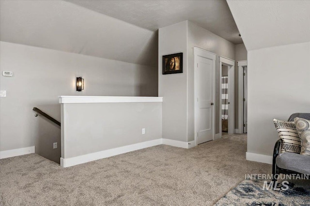 interior space with baseboards, vaulted ceiling, and carpet flooring