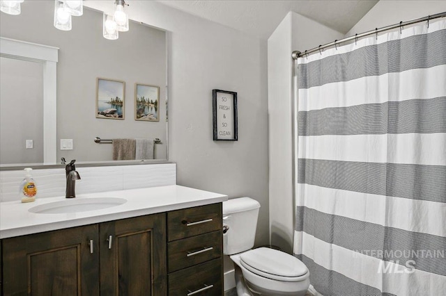 bathroom featuring toilet, lofted ceiling, and vanity