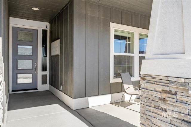 view of exterior entry with board and batten siding and covered porch