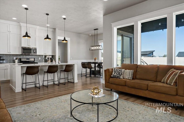 living room featuring recessed lighting, a textured ceiling, and wood finished floors