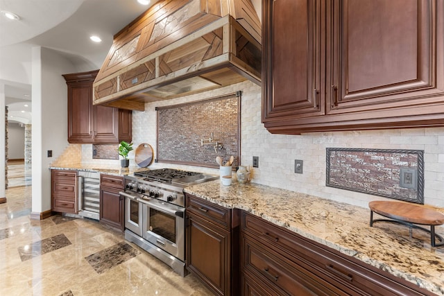 kitchen with double oven range, wine cooler, light stone countertops, tasteful backsplash, and custom range hood