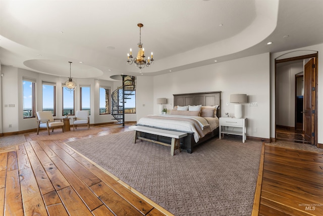 bedroom featuring a notable chandelier, dark hardwood / wood-style flooring, and a tray ceiling