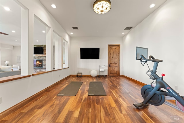 exercise room with wood-type flooring and a fireplace