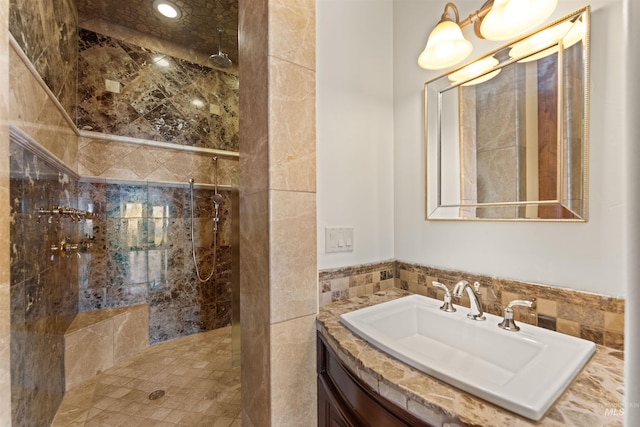 bathroom featuring tiled shower, vanity, and tile walls