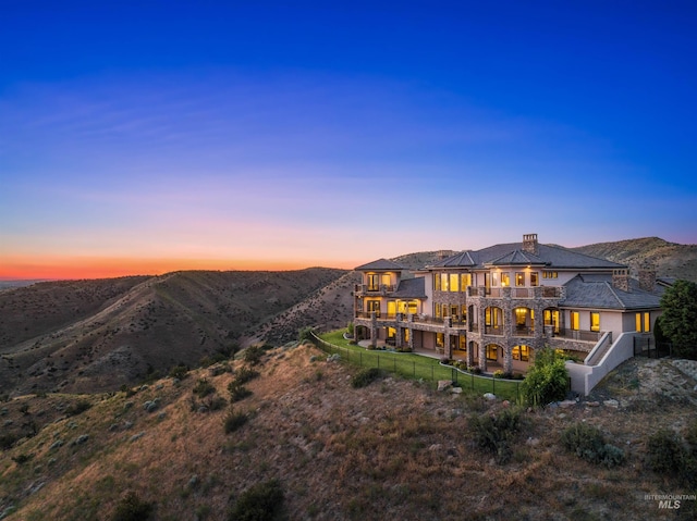 back house at dusk with a mountain view and a balcony