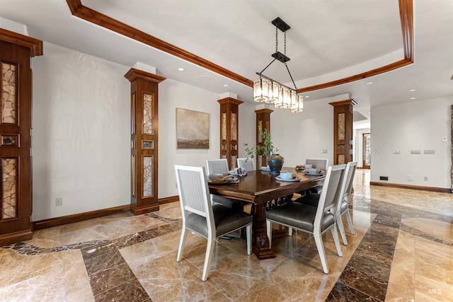 dining area with a chandelier, a tray ceiling, and decorative columns