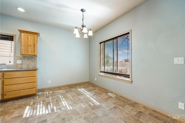 unfurnished dining area featuring a notable chandelier, baseboards, and visible vents