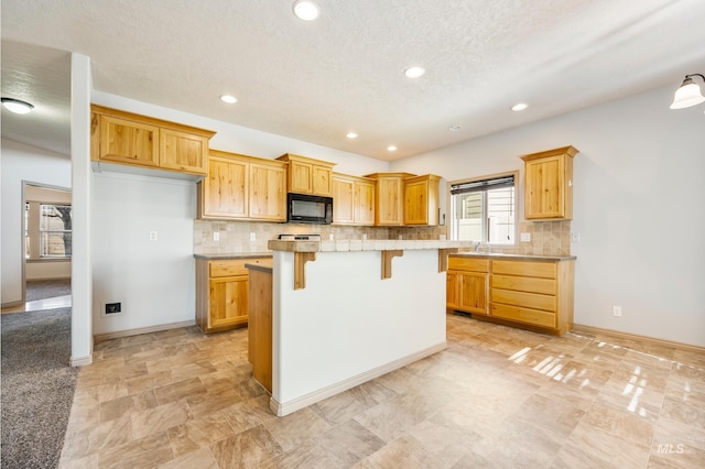 kitchen with tasteful backsplash, a kitchen island, black microwave, light countertops, and a kitchen breakfast bar