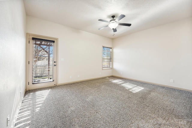 carpeted spare room featuring a healthy amount of sunlight, a textured ceiling, a ceiling fan, and baseboards