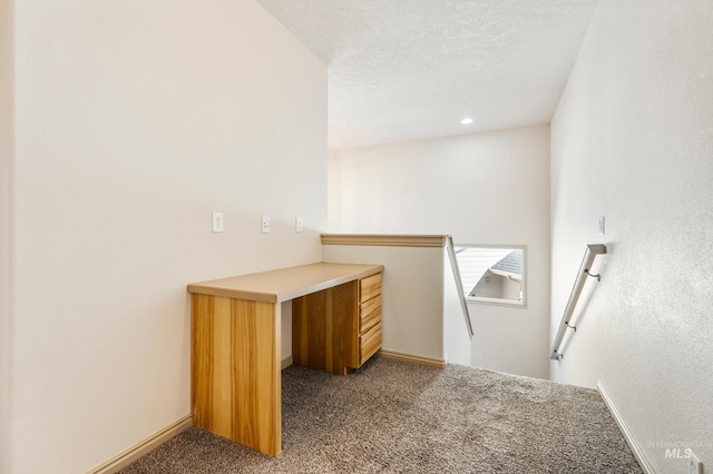 interior space with a textured ceiling, baseboards, and carpet floors