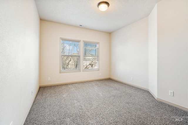 empty room with visible vents, a textured ceiling, baseboards, and carpet floors