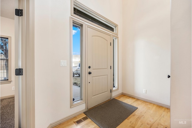 foyer entrance featuring visible vents, baseboards, and wood finished floors