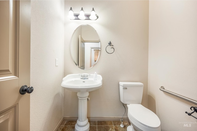 half bath with tile patterned floors, baseboards, and toilet