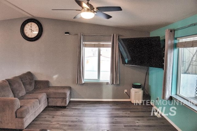 living room featuring a ceiling fan, vaulted ceiling, baseboards, and wood finished floors