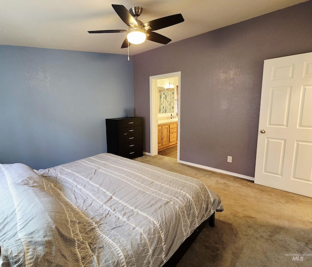 bedroom featuring light carpet, ceiling fan, baseboards, and ensuite bathroom