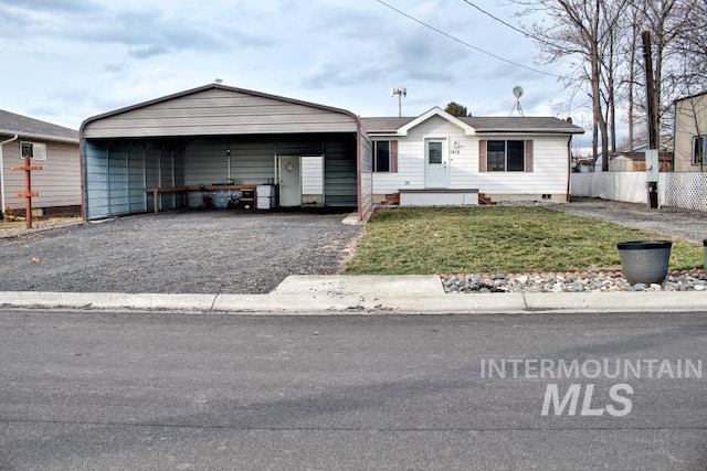 view of front of house with fence, driveway, crawl space, a detached carport, and a front lawn