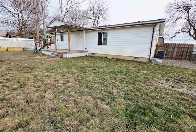 back of property with a deck, a playground, fence, a yard, and crawl space