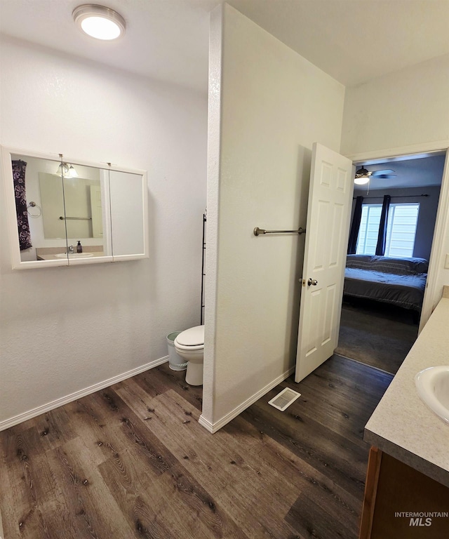 bathroom featuring toilet, baseboards, wood finished floors, and vanity