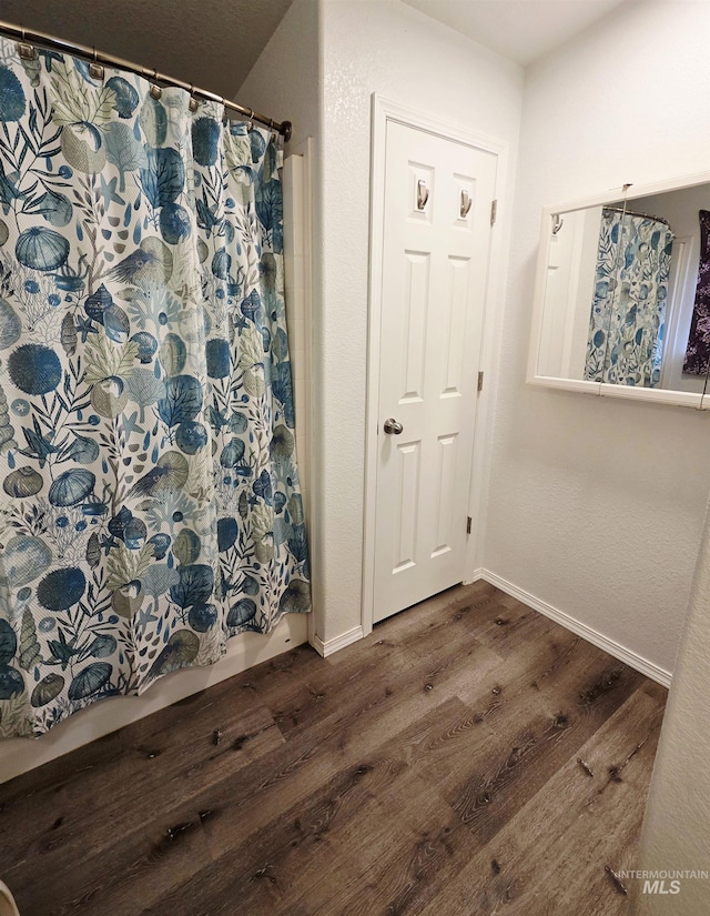 full bathroom with shower / tub combo with curtain, wood finished floors, and baseboards