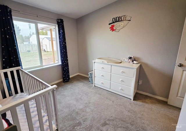 bedroom featuring carpet, a crib, and baseboards