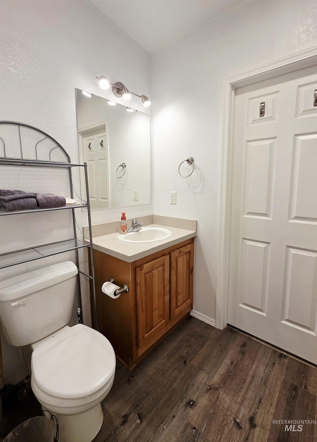 bathroom with toilet, wood finished floors, and vanity