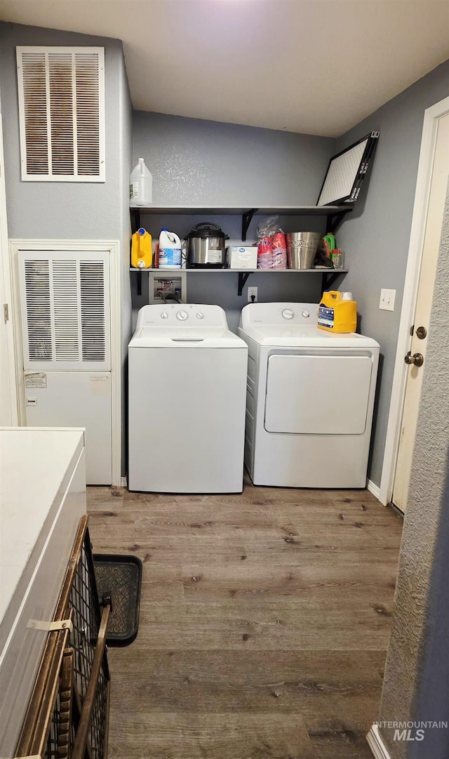 laundry room with laundry area, visible vents, separate washer and dryer, and wood finished floors