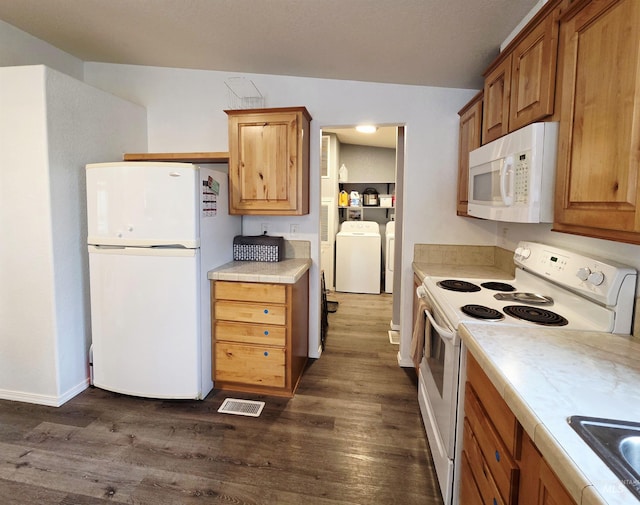 kitchen featuring white appliances, dark wood-type flooring, washing machine and clothes dryer, and visible vents