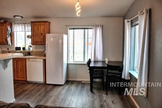 kitchen with tile counters, white appliances, brown cabinets, and wood finished floors