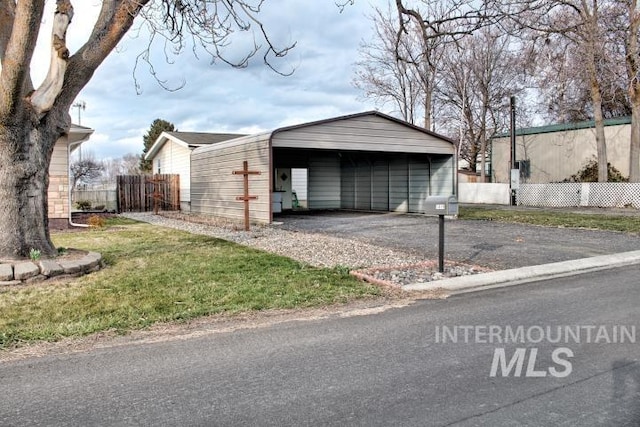 exterior space with aphalt driveway, a yard, fence, and a carport