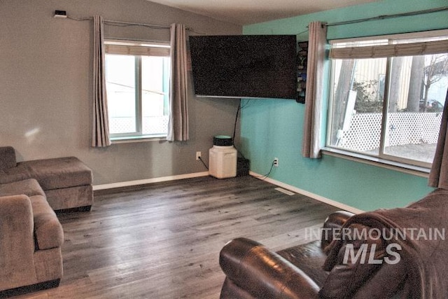 living room with a wealth of natural light, baseboards, and wood finished floors