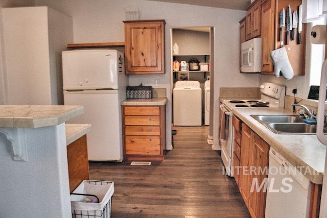 kitchen with brown cabinets, white appliances, a sink, and washer and dryer