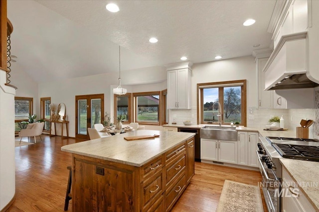 kitchen with pendant lighting, a kitchen island, white cabinetry, and sink