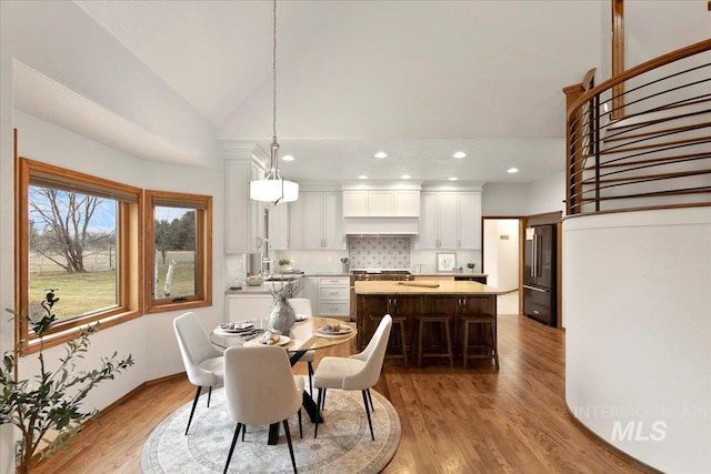 dining space featuring hardwood / wood-style flooring, lofted ceiling, and sink