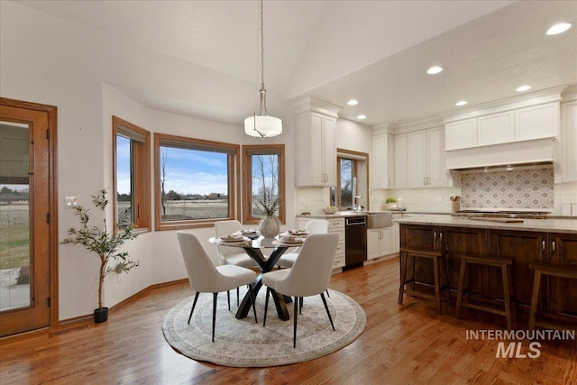 dining space with light wood-type flooring and lofted ceiling