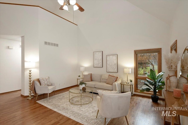 living room with hardwood / wood-style floors, high vaulted ceiling, and ceiling fan