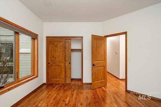 unfurnished bedroom with hardwood / wood-style floors, a textured ceiling, and a closet