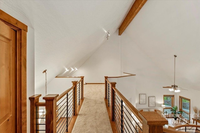 hallway with beam ceiling, light carpet, and high vaulted ceiling