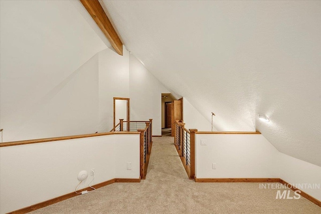 bonus room featuring lofted ceiling with beams, light colored carpet, and a textured ceiling