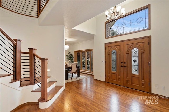 entrance foyer featuring hardwood / wood-style floors, ornamental molding, a high ceiling, and an inviting chandelier