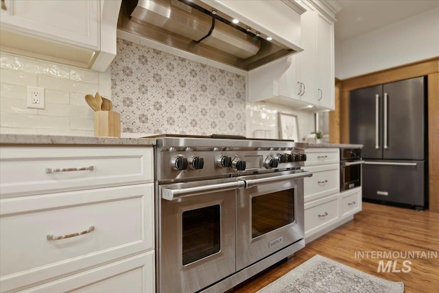 kitchen featuring tasteful backsplash, white cabinetry, custom exhaust hood, and premium appliances