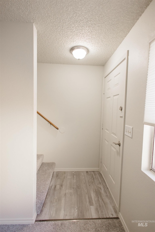 stairs with hardwood / wood-style floors and a textured ceiling