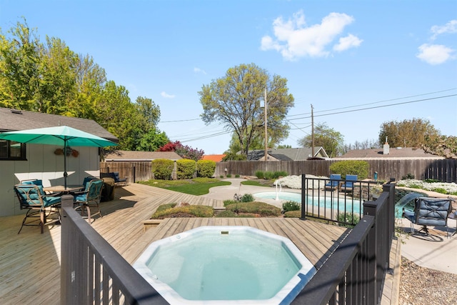 view of swimming pool with an outdoor hot tub, a deck, outdoor dining area, and a fenced backyard