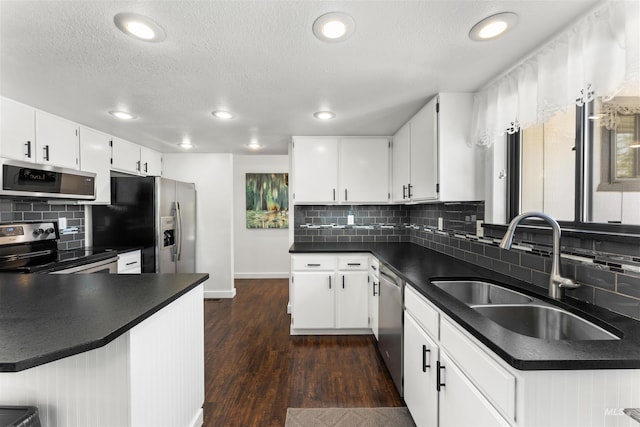 kitchen with dark countertops, baseboards, a sink, appliances with stainless steel finishes, and backsplash