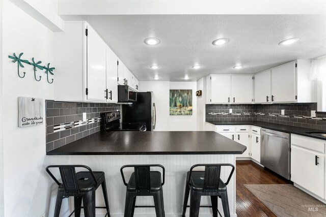 kitchen with dark countertops, electric range oven, stainless steel dishwasher, and a peninsula