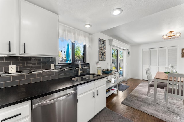 kitchen with decorative backsplash, dark countertops, dishwasher, a sink, and white cabinets