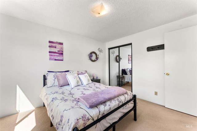 bedroom with a closet, a textured ceiling, and light colored carpet